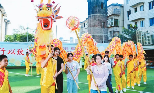 營(yíng)員們?cè)邶垘r學(xué)院附屬小學(xué)與學(xué)生一同舞龍。龍巖市融媒體中心供圖
